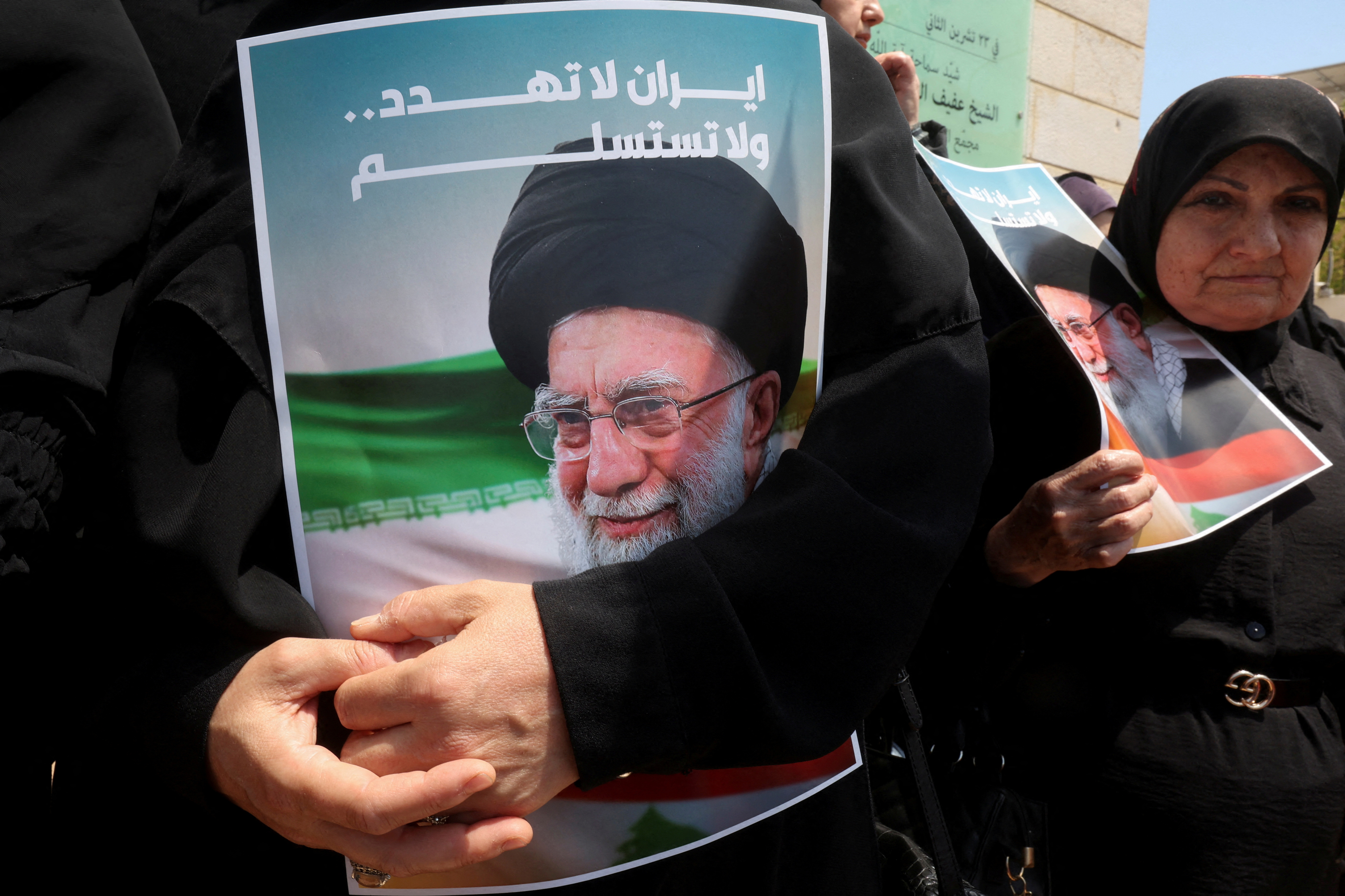 אישה אוחזת בתמונתו של המנהיג העליון של איראן עלי חמינאי