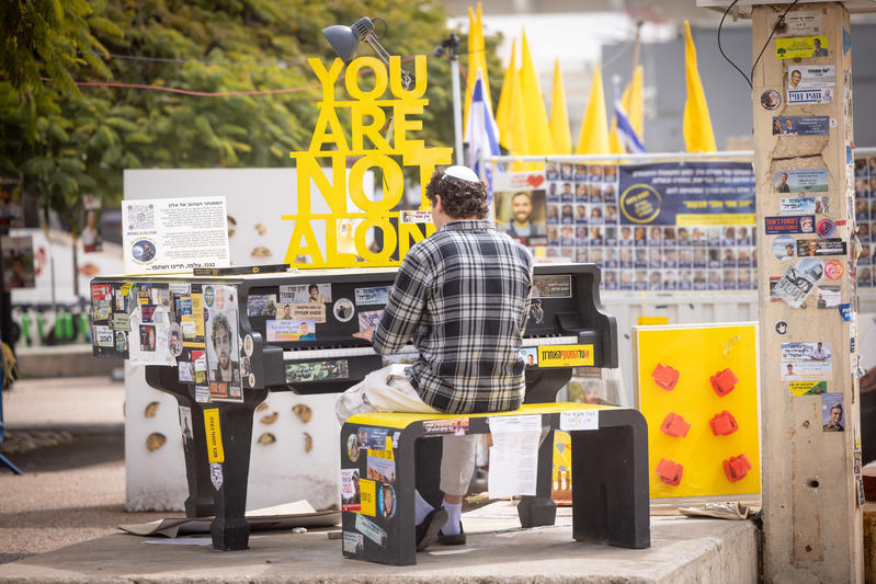אדם מנגן על פסנתר בכיכר החטופים בתל אביב