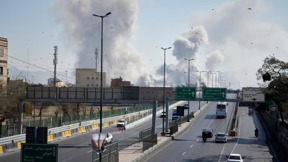 מכוניות נוסעות בכביש באיראן, כשברקע פטריות עשן