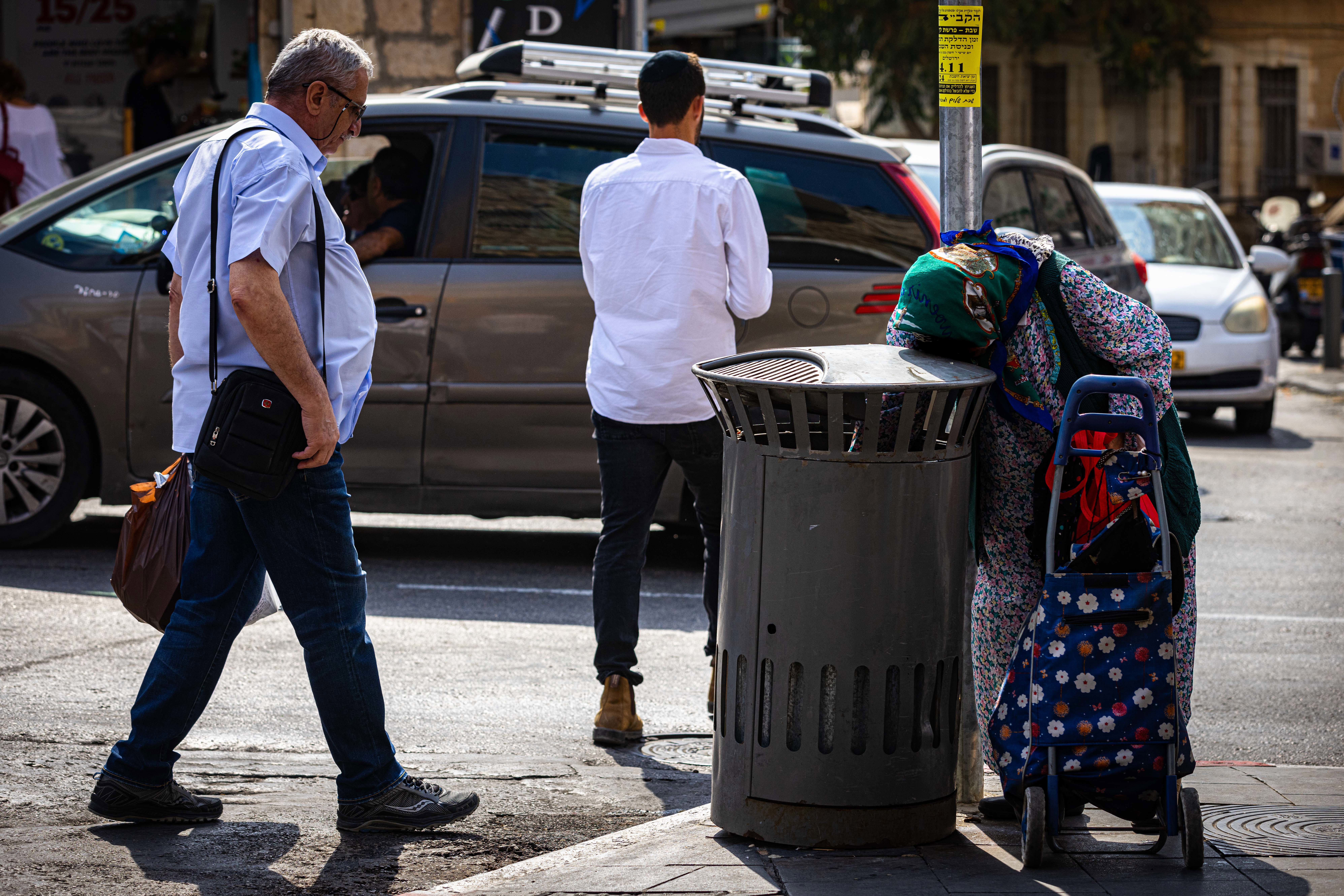 אישה מבוגרת מחפשת פחיות בפח אשפה